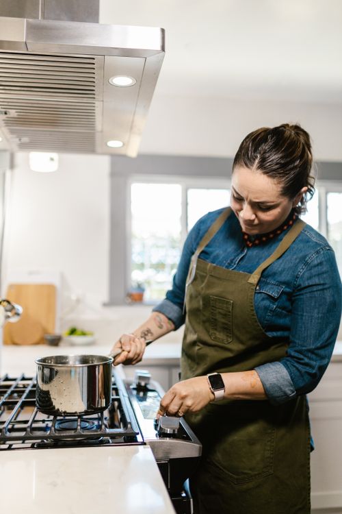 Woman Using Cooker in Domestic Kitchen · Free Stock Photo