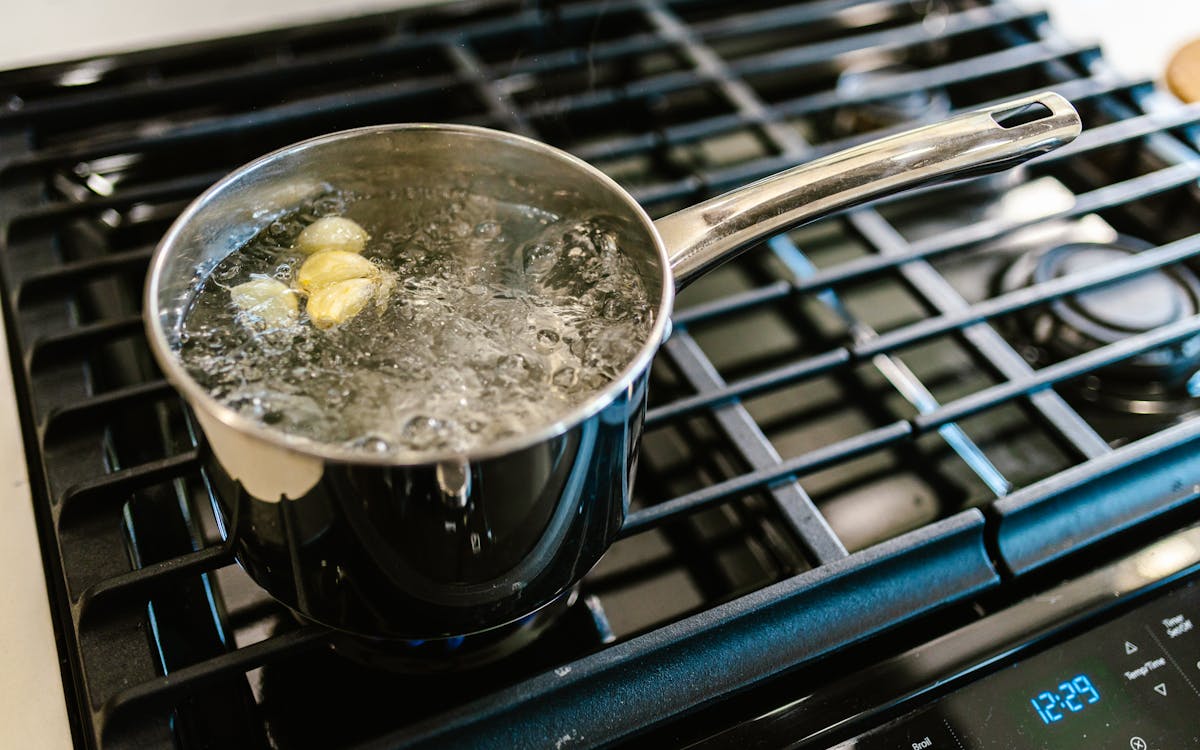 Close-up of garlic boiling in a pot on a stove, showcasing culinary preparation.