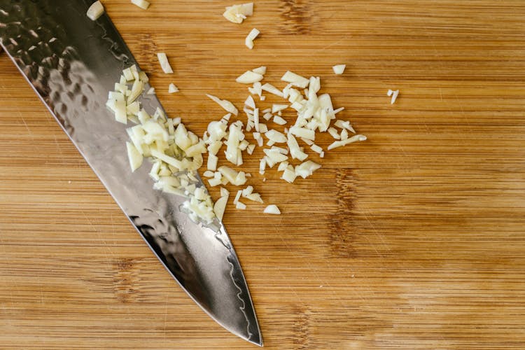 Knife With Chopped Garlic On Cutting Board