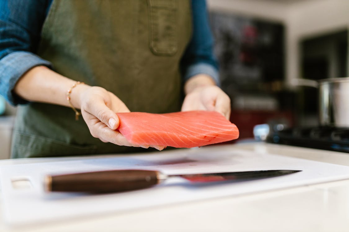 Woman Holding Slice of Salmon