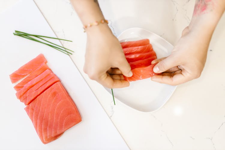 Arranging Slices Of Raw Fish On Plate