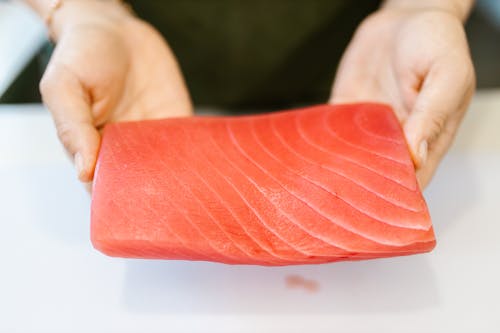 Woman Holding Slice of Salmon