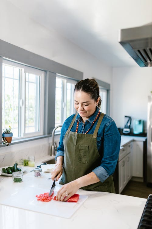 Woman Slicing Raw Fish in Domestic Kitchen