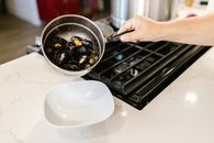 Hand Holding Pot with Boiled Mussels