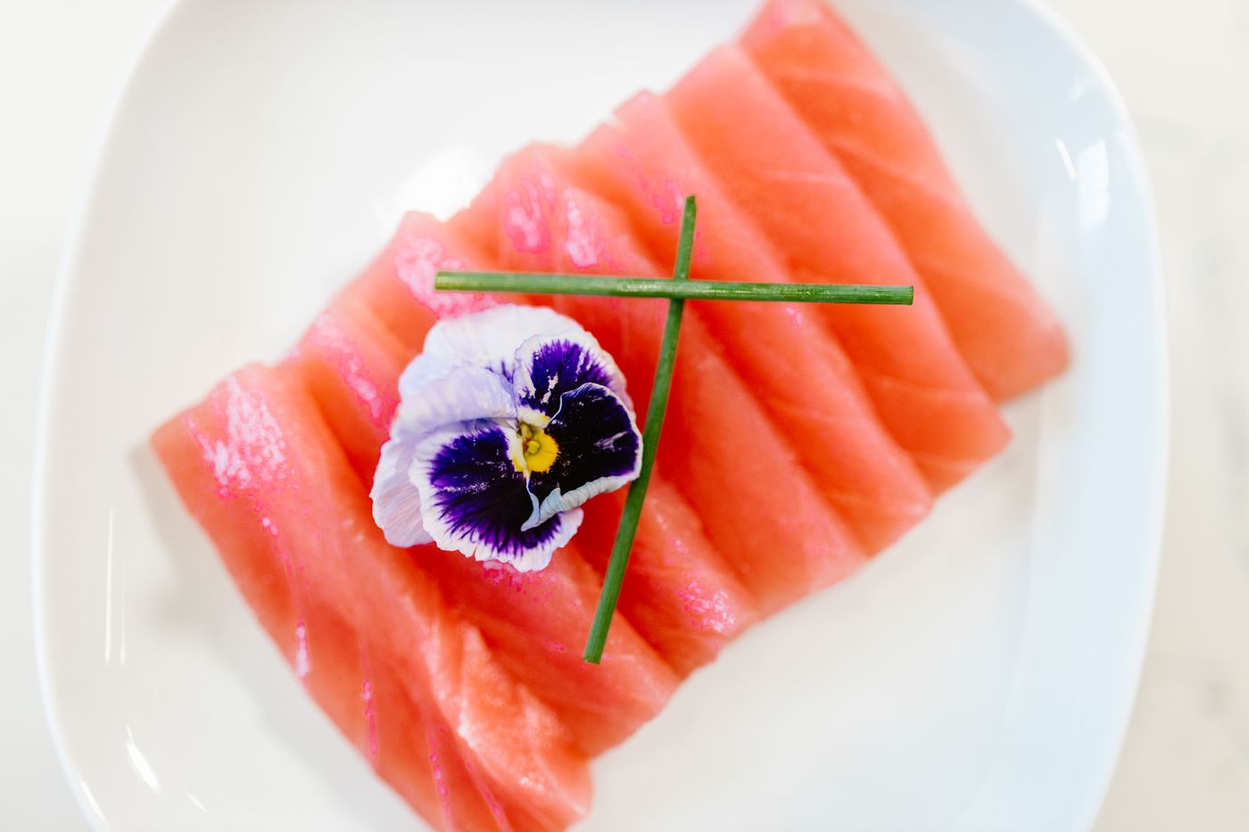 Fette di sashimi con erba cipollina e un fiore edibile