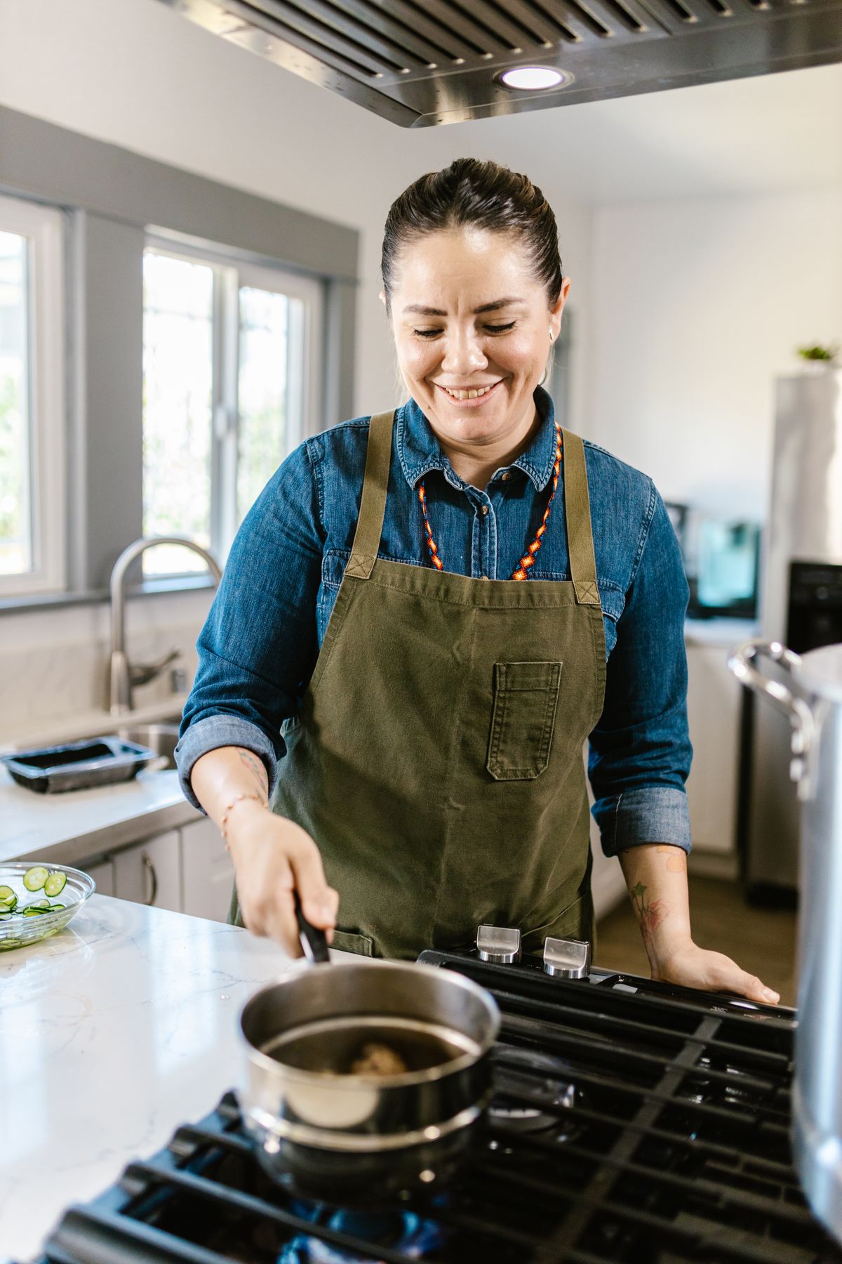 A home cook smiling while preparing a meal in a bright kitchen