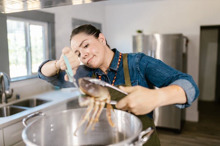 Woman Holding Crab Over Pot