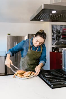 A woman in an apron prepares crabs in a modern kitchen setting, focusing on seafood cooking.