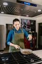 Female Chef in Apron Pouring Oil on Frying Pan 