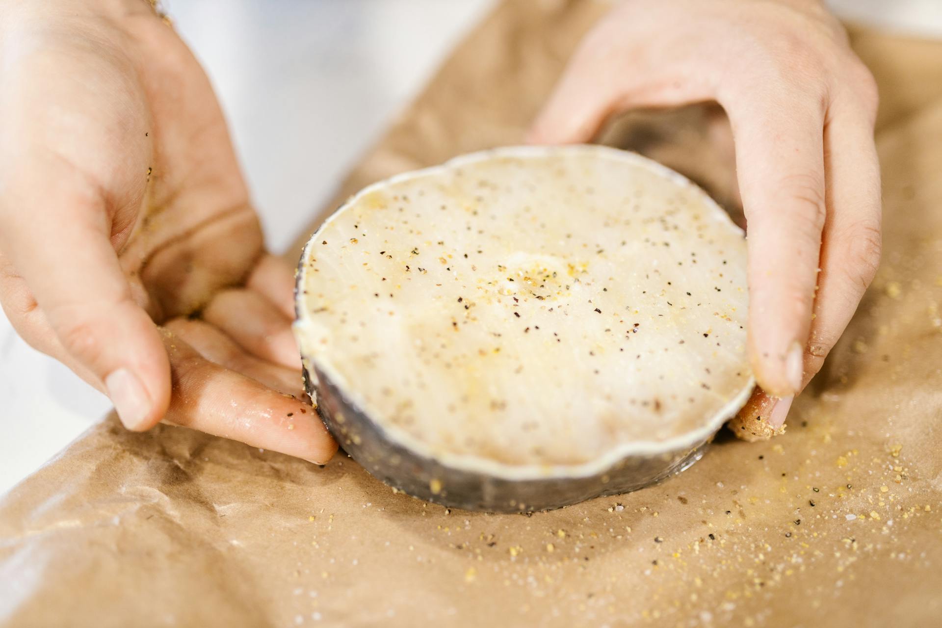 Hands Holding Seasoned Piece of Raw Fish