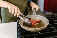Cook Frying Slice of Red Tuna Fish Meat on Gas Cooker
