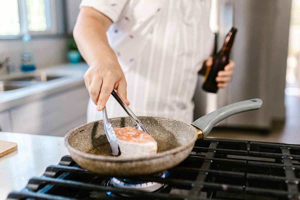 Chef che cuoce un trancio di salmone in padella antiaderente