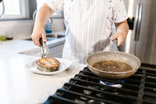 A home cook places a grilled salmon steak on a plate in a modern kitchen setting.