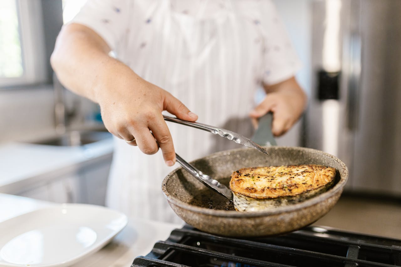 Filetto di pesce in padella sopra fornello durante cottura veloce