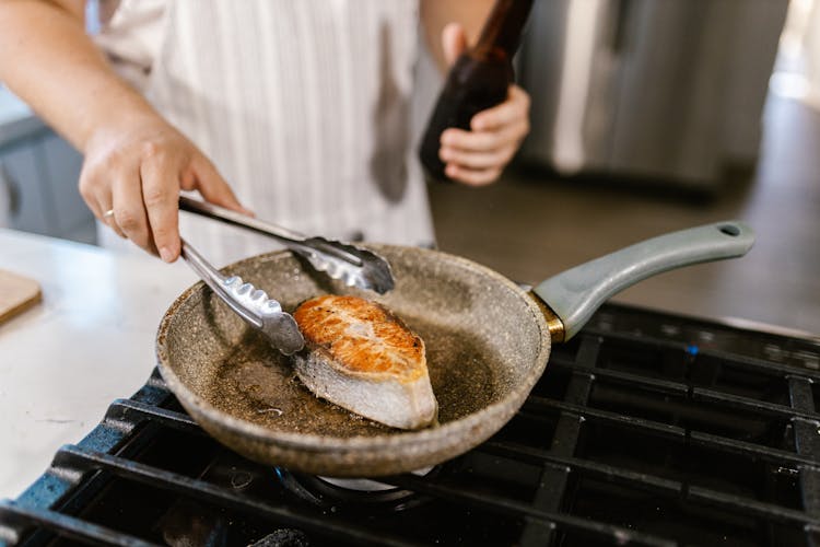 Unrecognizable Chef Preparing Fish Slice On Frying Pan