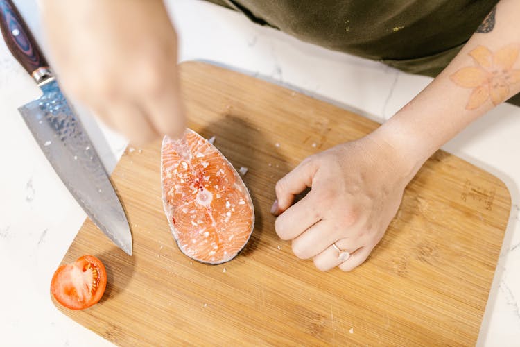 Slice Of Salmon Laying On Cutting Board Sprinkled With Salt