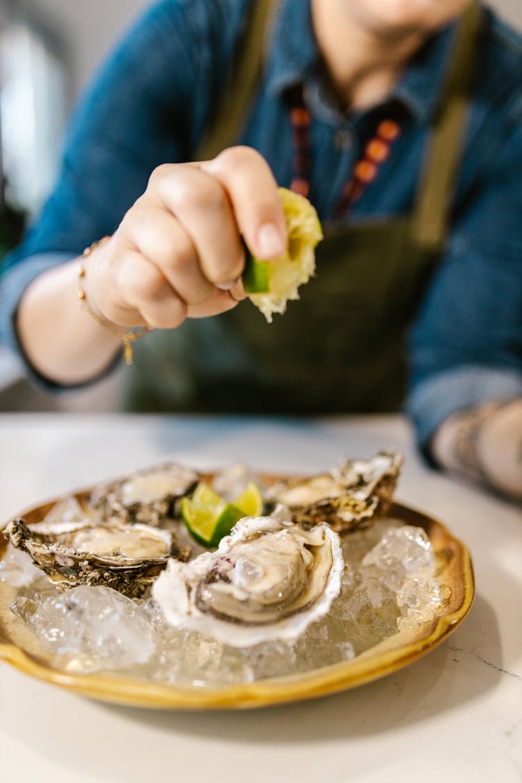 Chef Squeezing Lime On Oysters Served With Ice