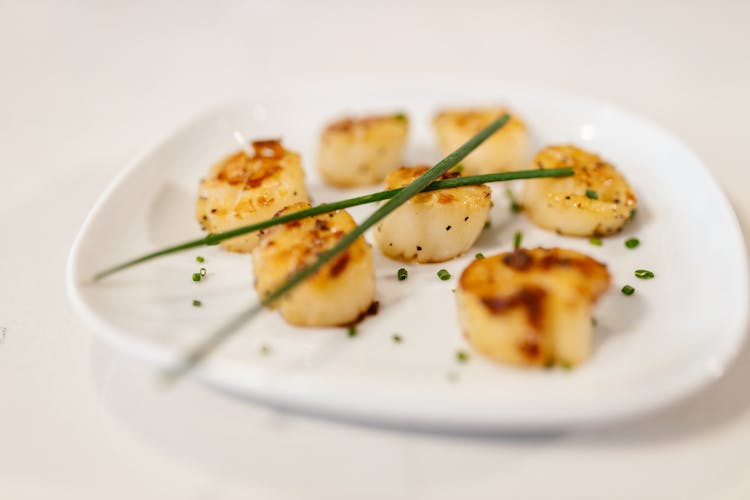 Fried Scallops With Herbs Served On White Plate