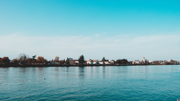 Serene landscape of Basel's riverside with clear blue sky and distant town skyline.