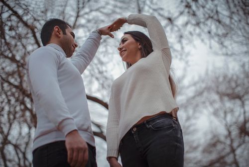 Free A happy couple dancing amidst bare trees, capturing romantic joy in a winter setting. Stock Photo