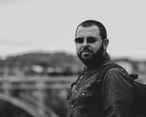Free Monochrome portrait of a man with sunglasses and backpack in Bern's urban setting. Stock Photo
