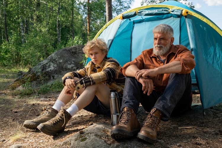 Grandfather And Grandson Camping In Forest