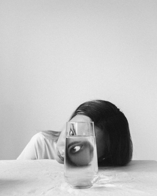 Free Artistic black and white portrait featuring a woman's face distorted through a glass of water, exploring creativity and perception. Stock Photo
