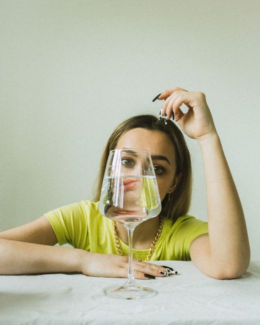 A woman sitting with face obscured by a glass, creating a fun and imaginative effect.