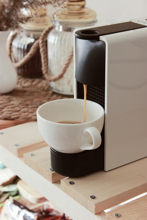 Free Close-up of a coffee machine brewing fresh espresso into a white cup on a wooden surface. Stock Photo