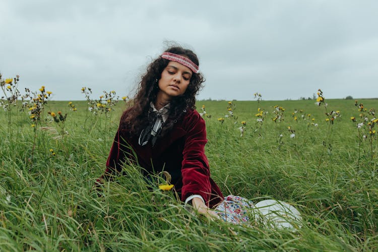 A Woman In Maroon Shirt Sitting On Green Grass Field