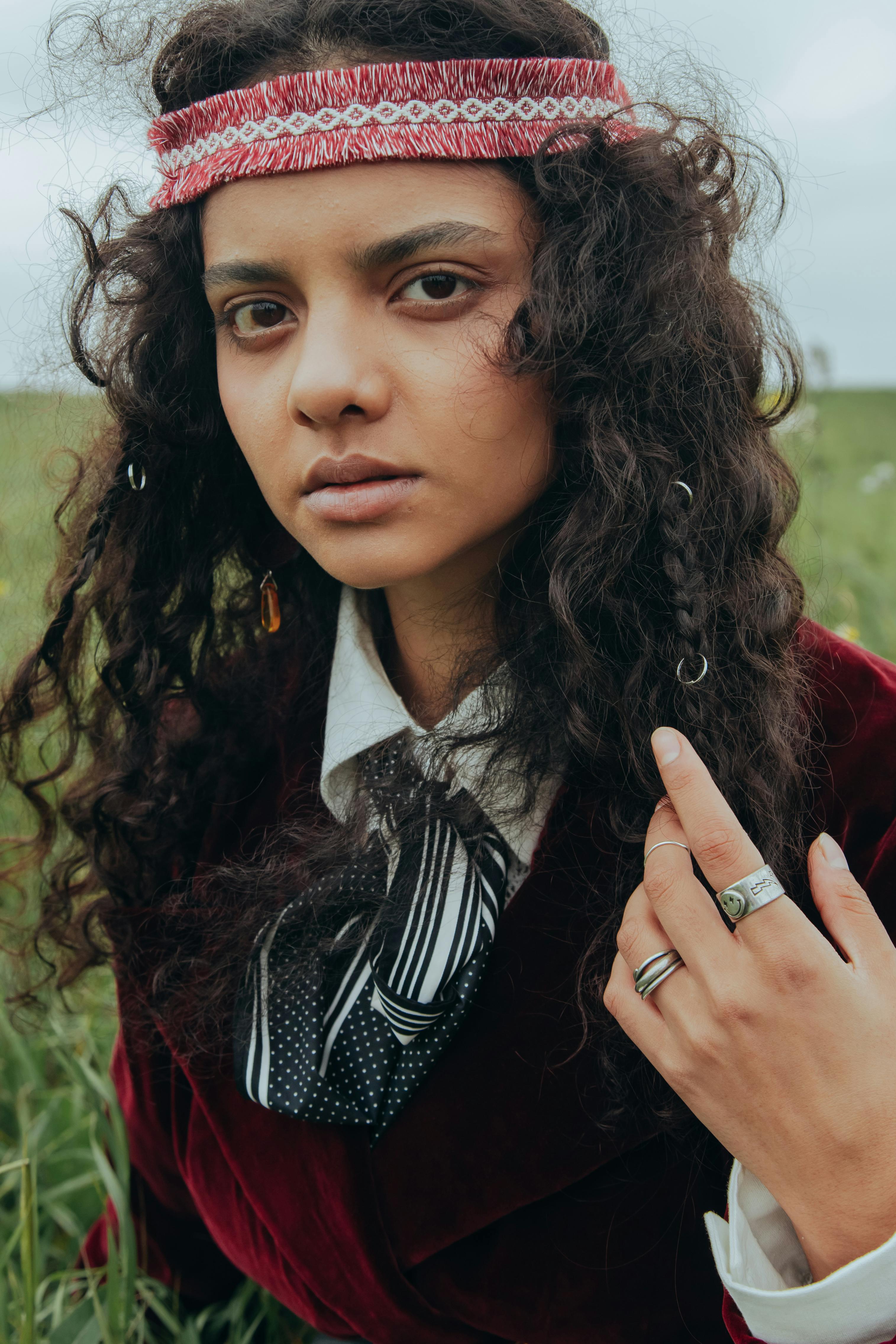 Captured in a natural setting, a woman with curly hair and bohemian attire poses.