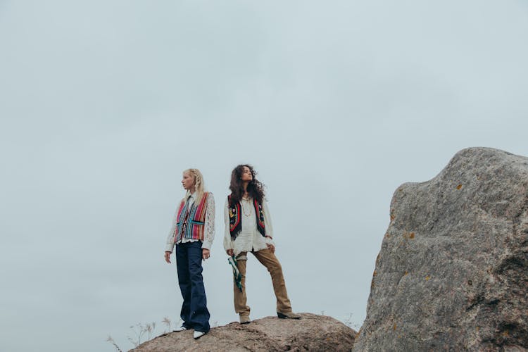 Women Standing Back To Back On Big Rock