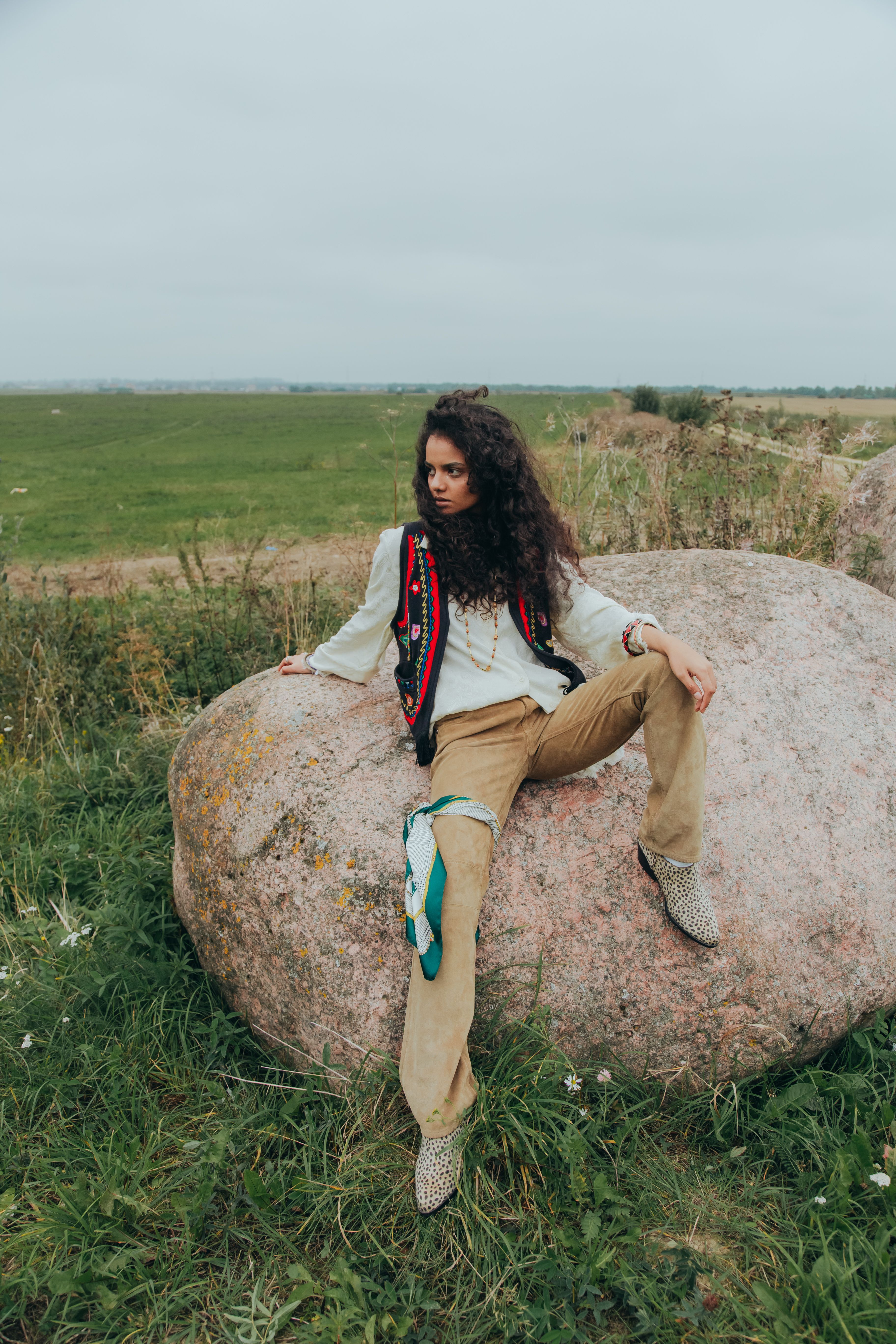 Woman with Curly Hair Sitting on a Rock · Free Stock Photo