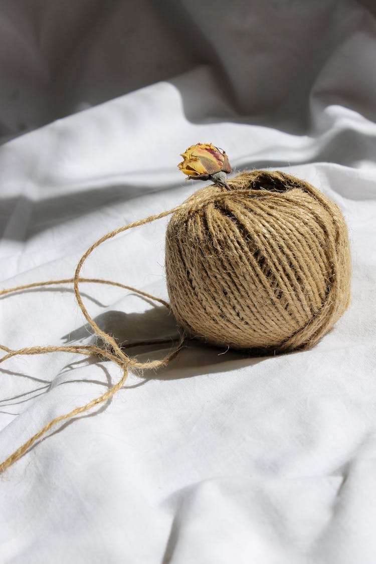 A Dried Flower In A Ball Of Brown Yarn