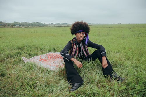 A Man with Afro Hair Sitting on Picnic Blanket