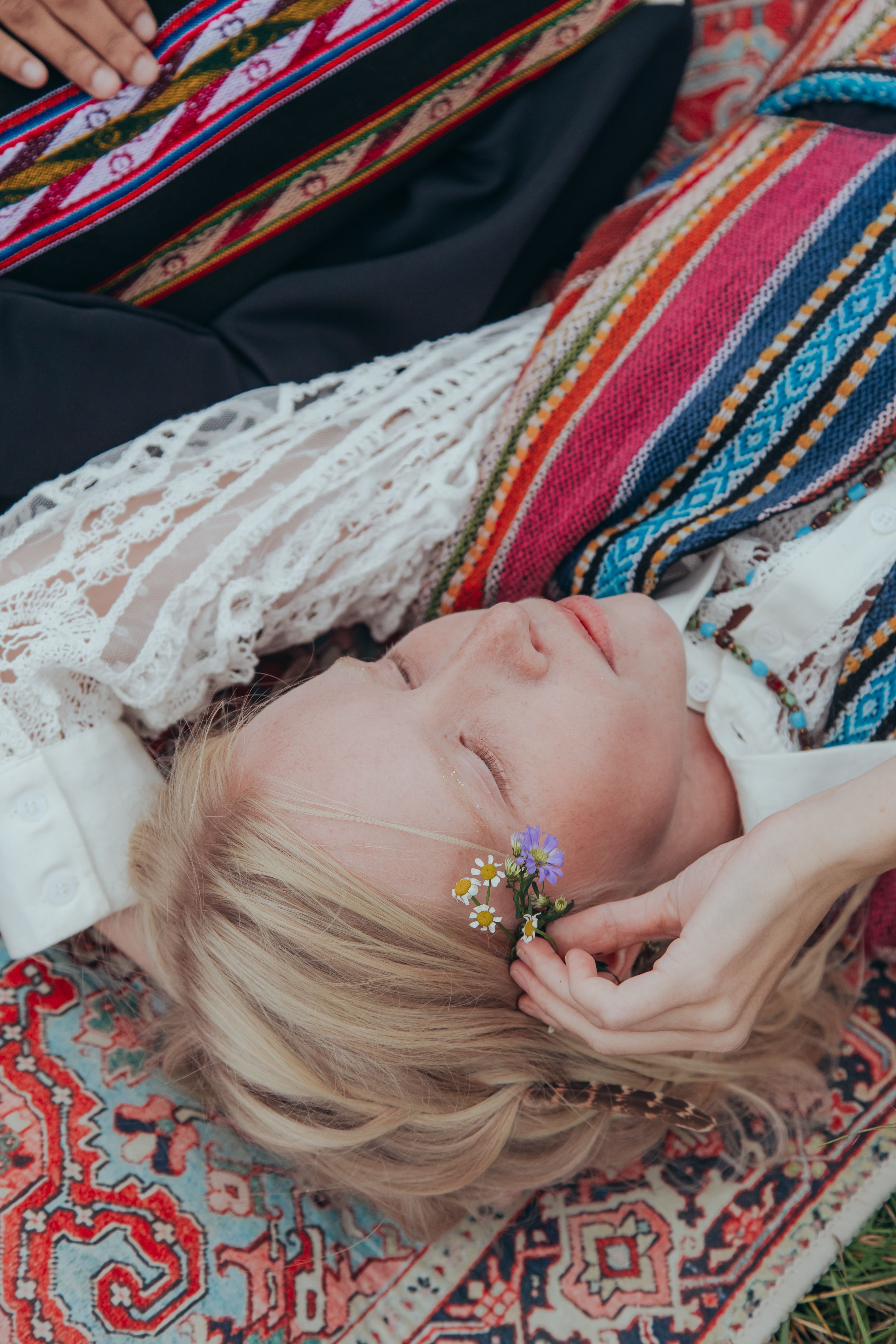 A serene portrait of a woman in traditional attire, lying on a vibrant ethnic blanket.