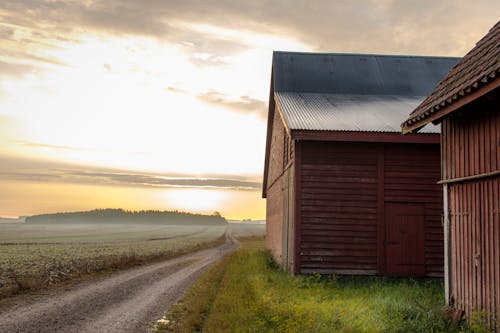 Free Brown Wooden Barn on Green Grass Field Under White Clouds Stock Photo