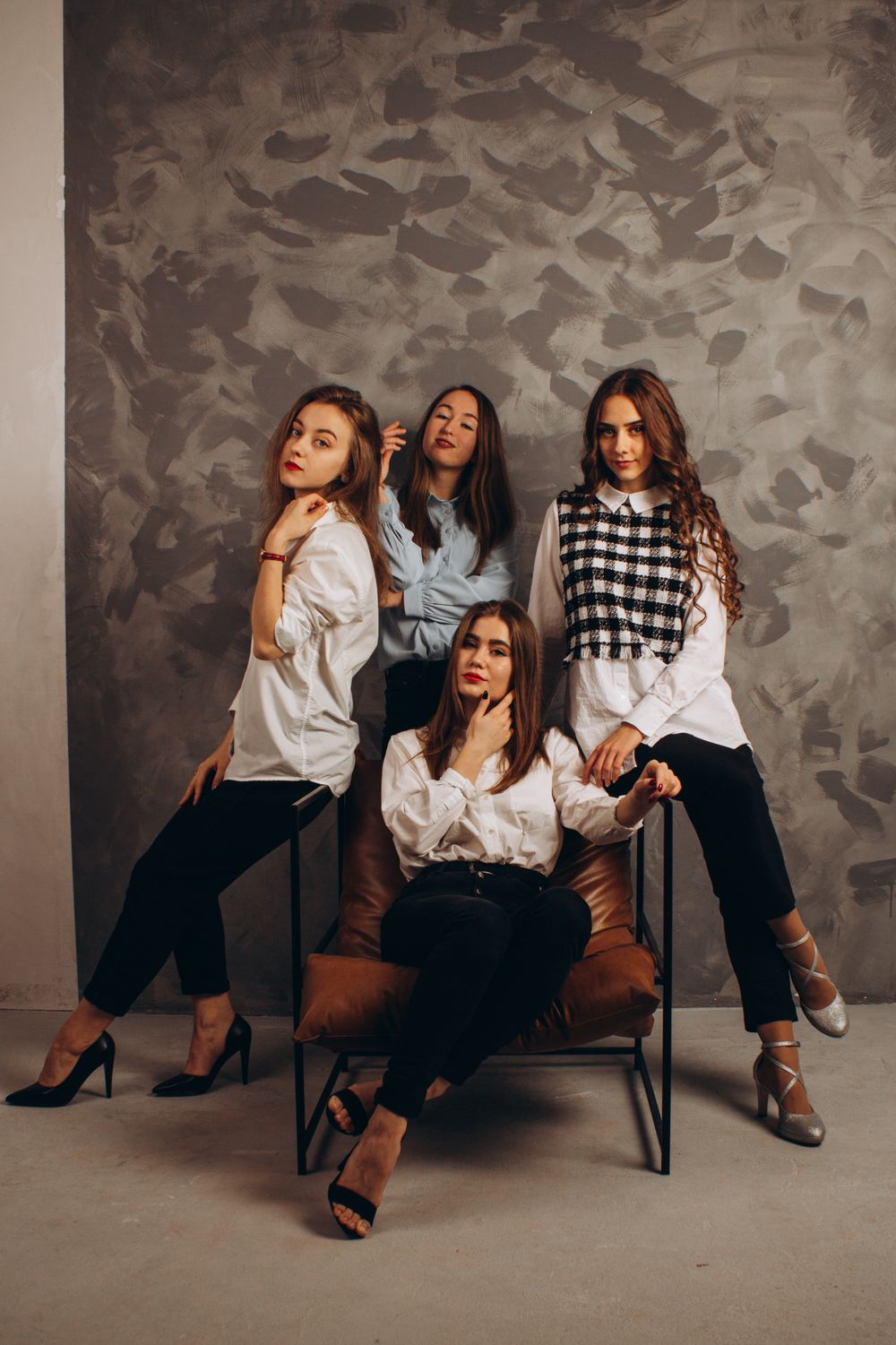 Five women in white blouses posing in a studio