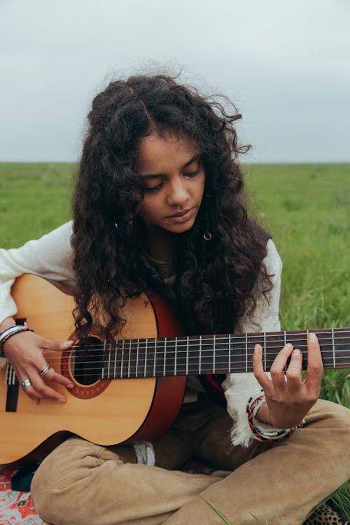 Young Woman Playing Guitar in a Grass Field
