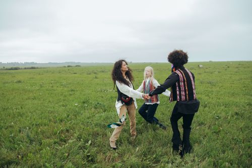 Free A group of diverse friends dancing joyfully in a lush green field. Stock Photo