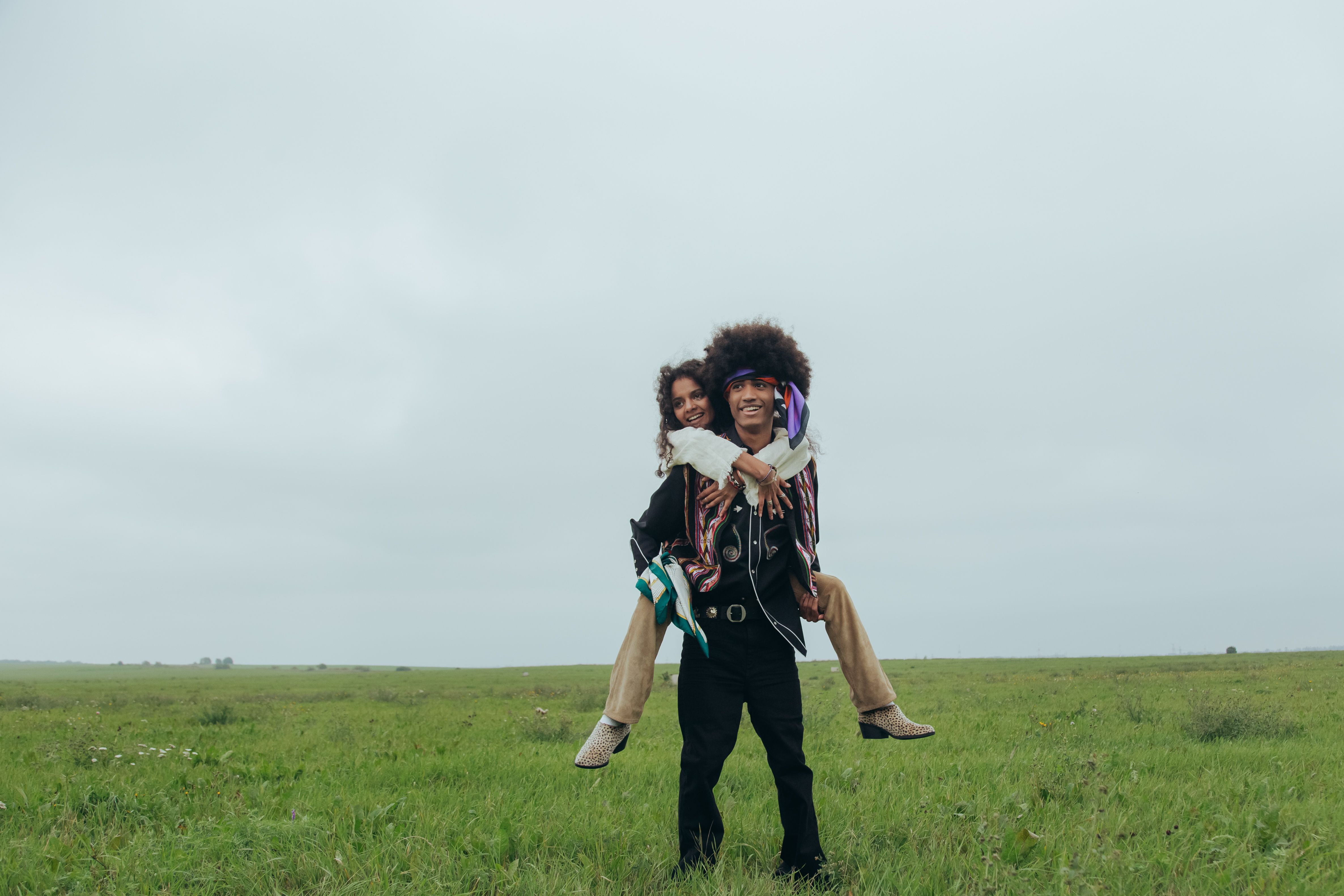 A cheerful couple enjoying a playful piggyback ride in a serene grass field.