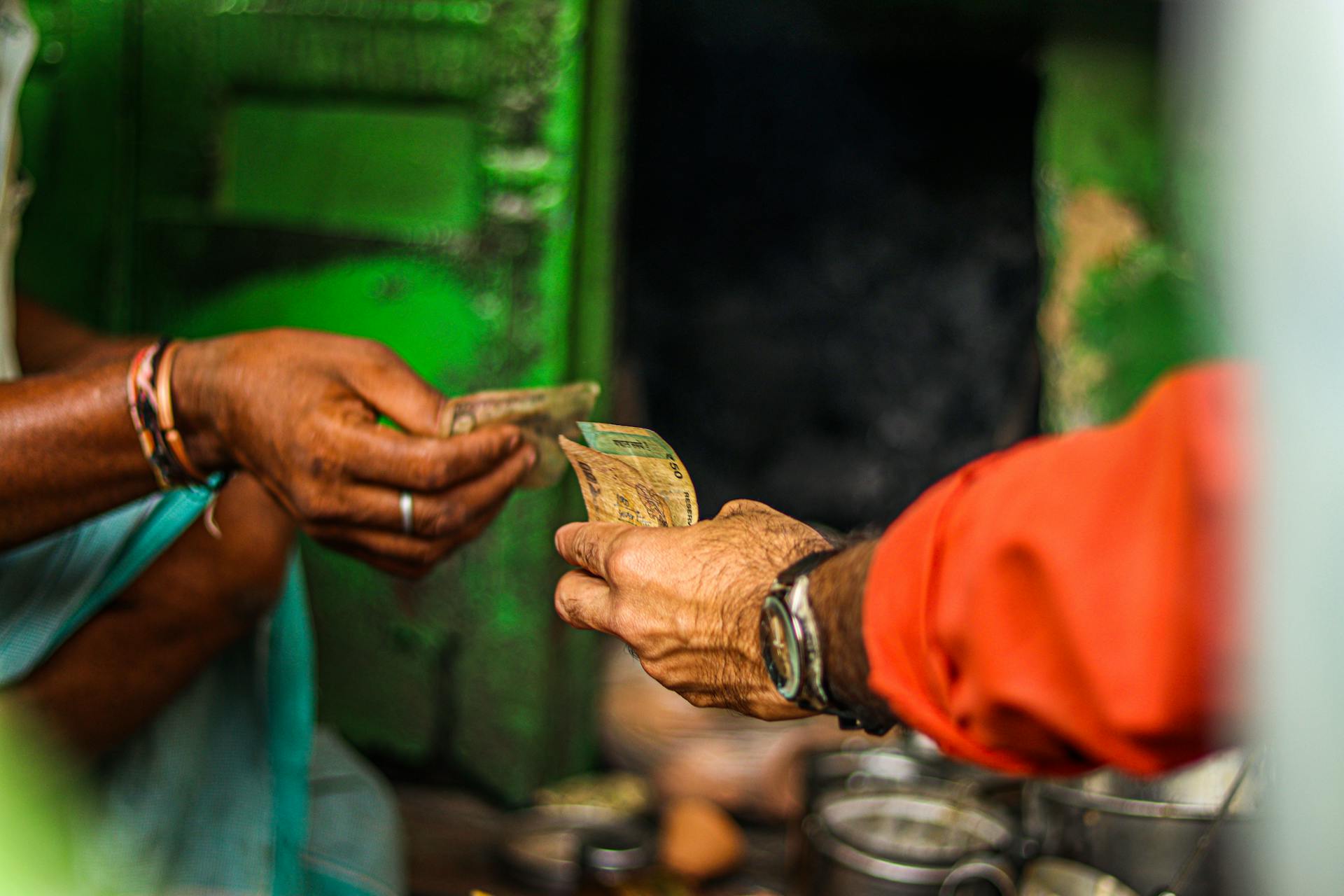 A close-up shot of two people exchanging currency in an outdoor market setting.