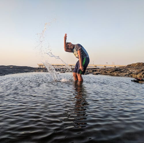 Free Boy Playing on Body of Water Stock Photo
