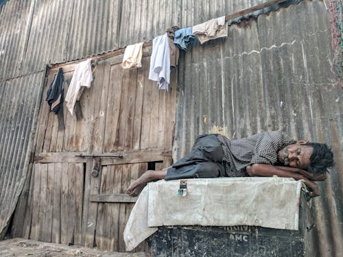 Free Man sleeping in front of a building Stock Photo