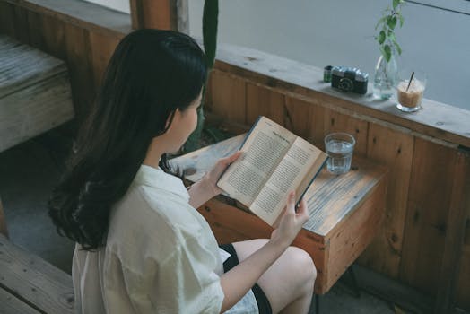 A serene moment of a woman reading indoors with natural light, perfect for relaxation themes.