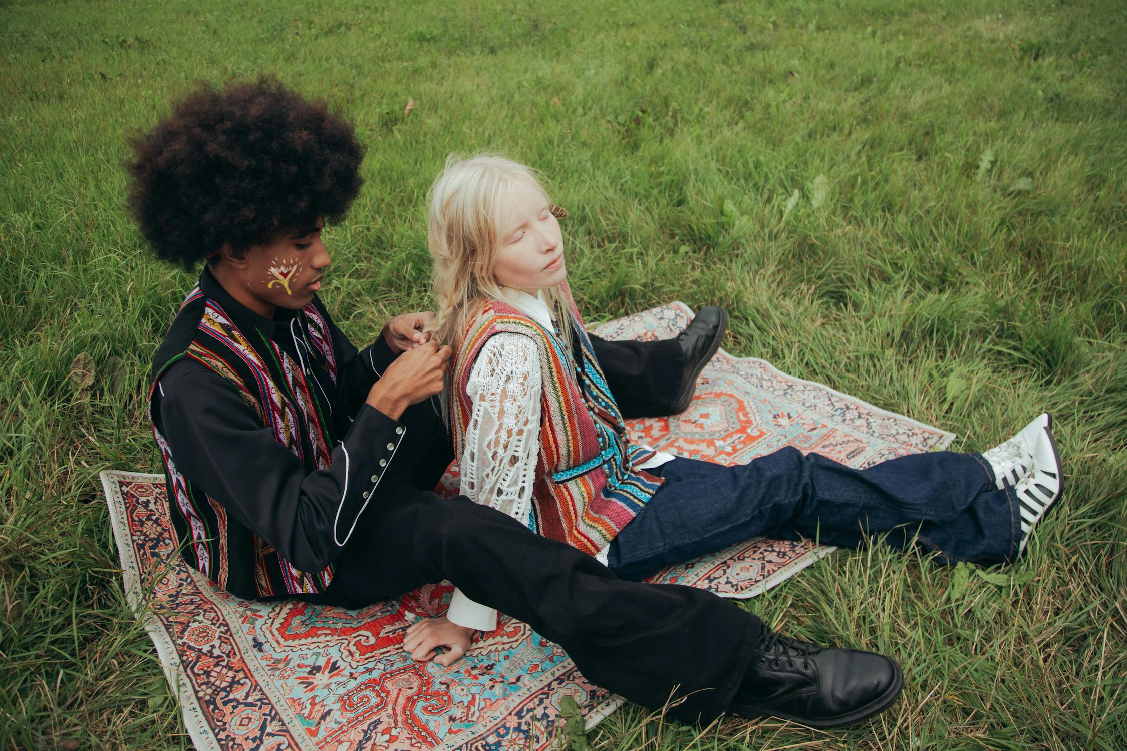 Deux personnes au look des années 70 assis dans l'herbe