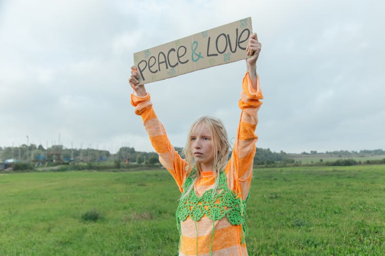 A Woman Raising Her Hands While Holding A Banner