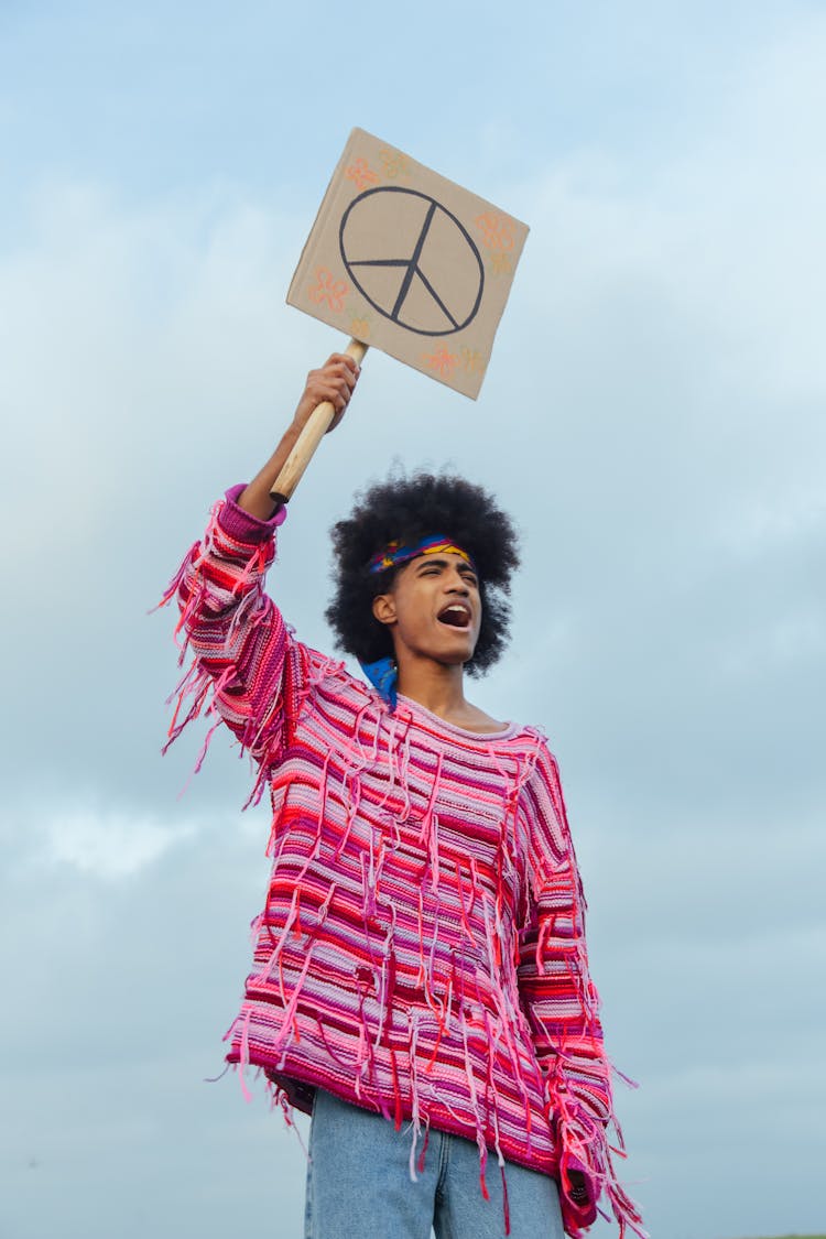 A Man In Striped Sweater Holding A Placard Yelling