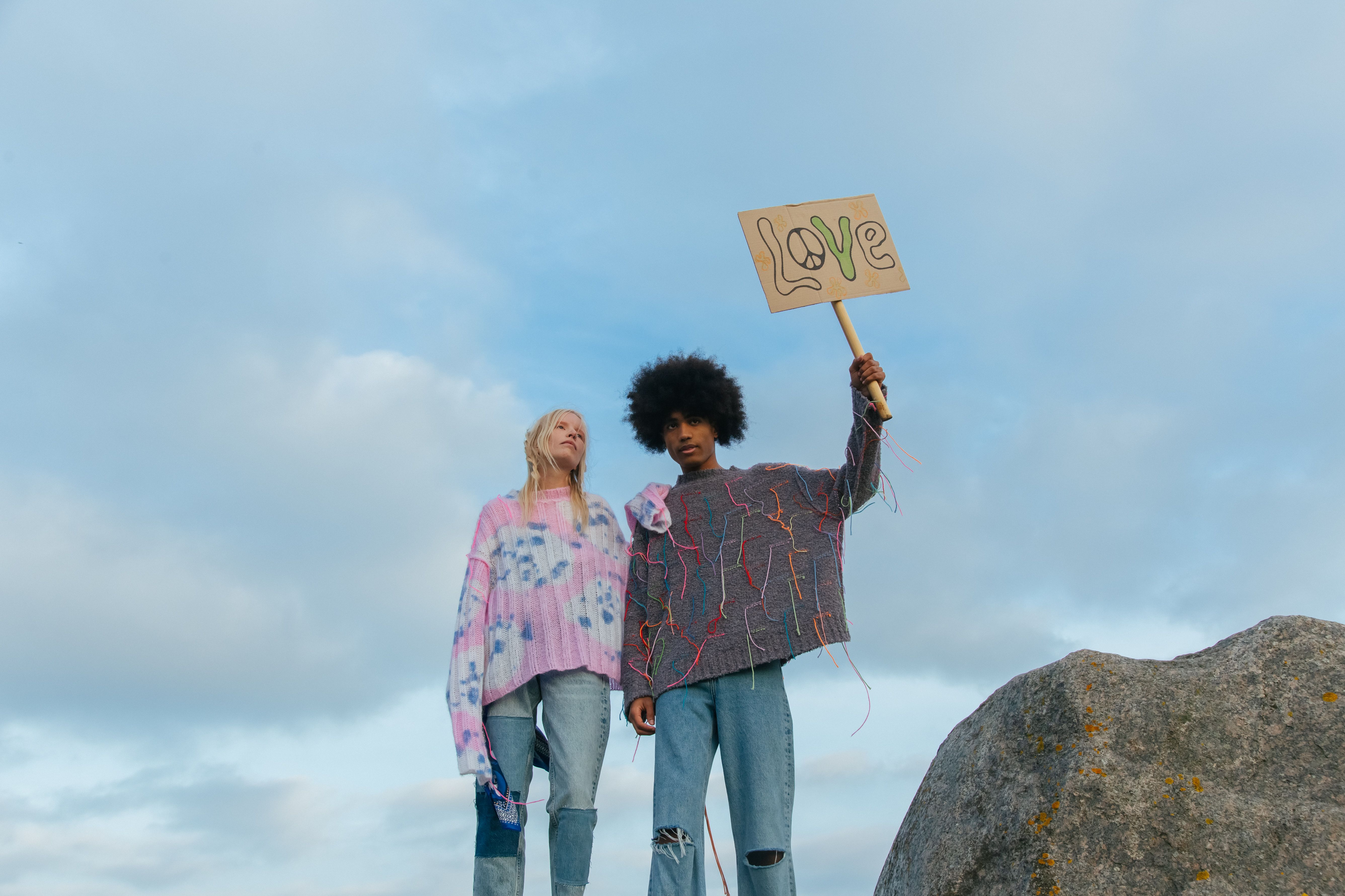 A couple standing outdoors holding a sign with the word 'love'.