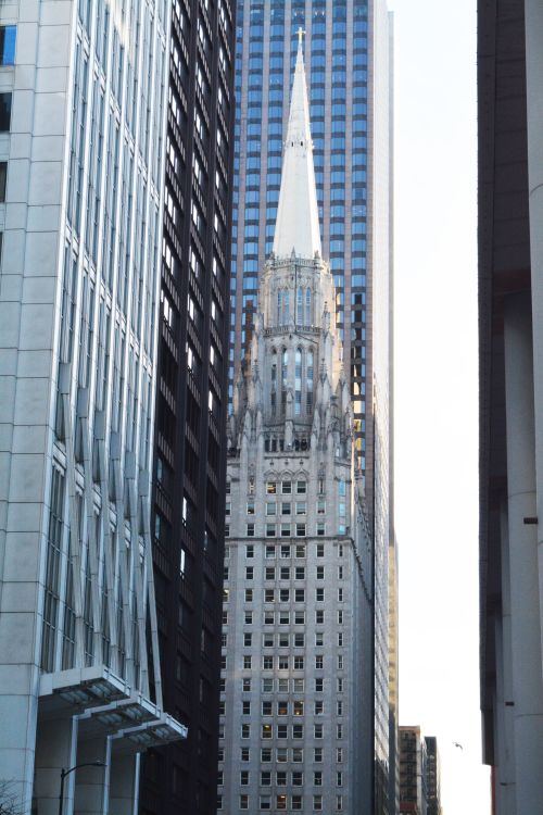 Free A striking view of a historic skyscraper with a spire amid modern Chicago architecture. Stock Photo